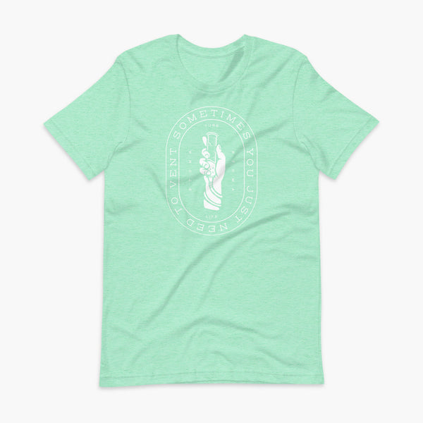 Text that says Sometimes You Just Need To Vent wrapping around a hand holding a syringe or venting tube that is connected to a g-tube or gastronomy tube and mic-key button. There is additional text that says StomaStoma and Tube Life. On a heather mint adult t-shirt.