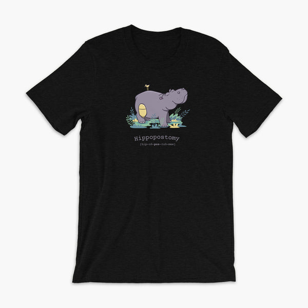 A Hippo or Hippopotamus with an ostomy bag — also known as a Hippopostomy. He is standing in some foliage smiling and has a bird on his back on a heather black adult t-shirt.