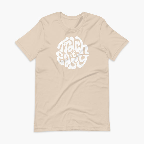 White text that says Trach It Easy for living the tracheostomy life with StomaStoma on a soft creme adult t-shirt 