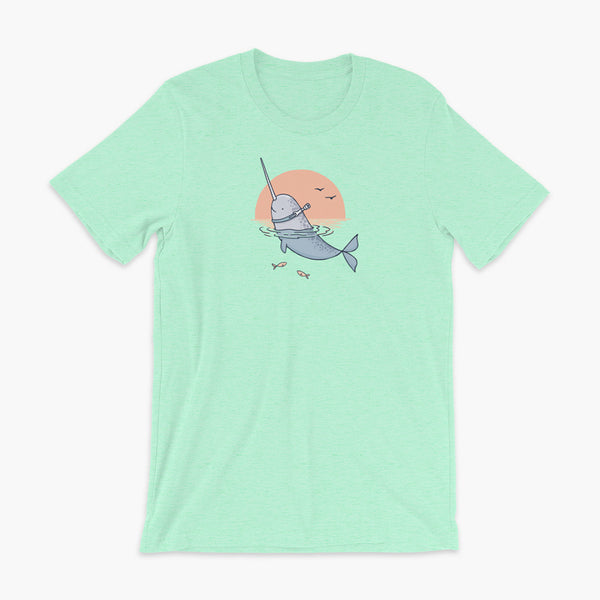 A Narwhal that has a trach or tracheostomy pokes his head and horn through the water in front of a setting sun. He has a naturally built in stoma. It is on a heather mint adult t-shirt.