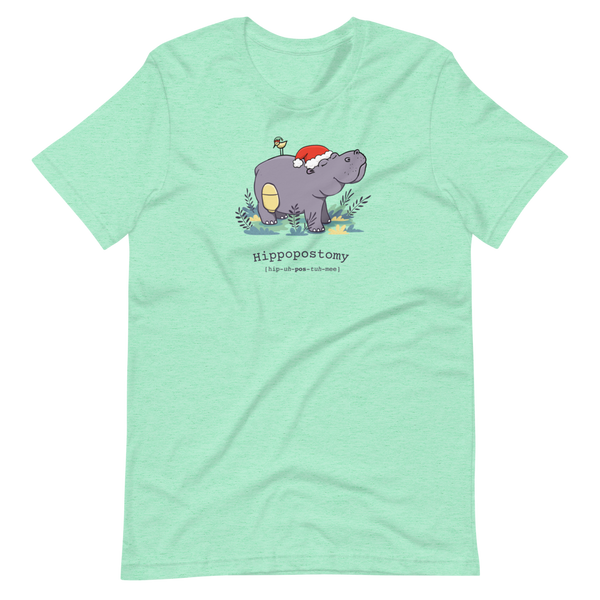 A Hippo or Hippopotamus with an ostomy bag — also known as a Hippopostomy. He is standing in some foliage smiling and has a bird on his back with a Christmas hat on a heather mint adult t-shirt.