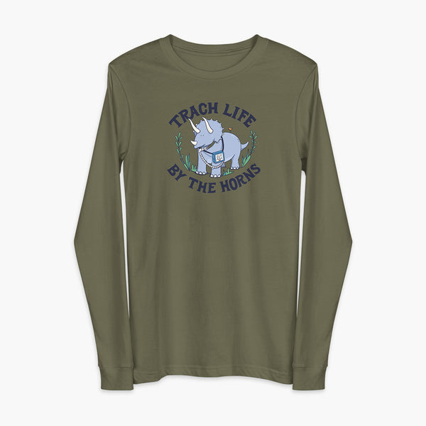 A happy triceratops dinosaur that has a trach or tracheostomy and a vent or ventillator to help him breathe. He also has a g-tube or gastronomy tube. There is text wrapping around the dinosaur that says Trach Life By The Horns. It is on a military green adult long sleeve t-shirt.