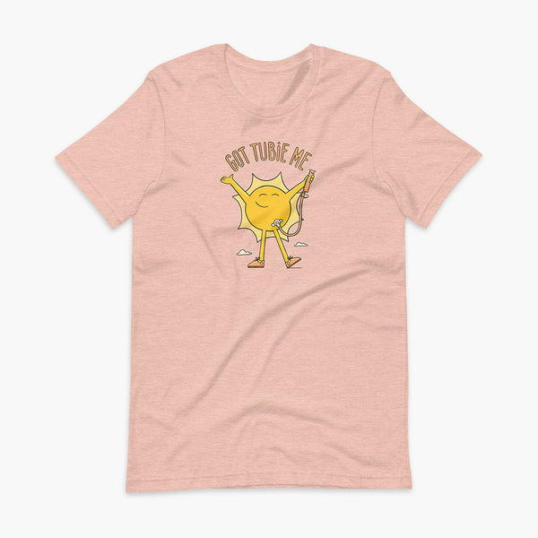 A happy sun stands confidently in tennis shoes holding a g-tube or a gastronomy tube with a stoma for StomaStoma with the text Got Tubie Me above him on an adult heather prims peach t-shirt 