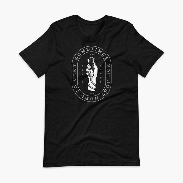 Text that says Sometimes You Just Need To Vent wrapping around a hand holding a syringe or venting tube that is connected to a g-tube or gastronomy tube and mic-key button. There is additional text that says StomaStoma and Tube Life. On a heather blackadult t-shirt.