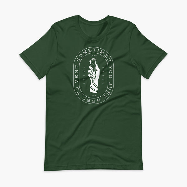 Text that says Sometimes You Just Need To Vent wrapping around a hand holding a syringe or venting tube that is connected to a g-tube or gastronomy tube and mic-key button. There is additional text that says StomaStoma and Tube Life. On a heather forest green adult t-shirt.