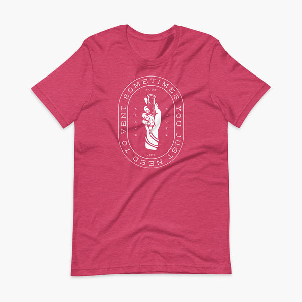 Text that says Sometimes You Just Need To Vent wrapping around a hand holding a syringe or venting tube that is connected to a g-tube or gastronomy tube and mic-key button. There is additional text that says StomaStoma and Tube Life. On a heather raspberry adult t-shirt.