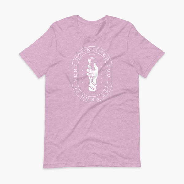 Text that says Sometimes You Just Need To Vent wrapping around a hand holding a syringe or venting tube that is connected to a g-tube or gastronomy tube and mic-key button. There is additional text that says StomaStoma and Tube Life. On a heather prism lilac adult t-shirt.
