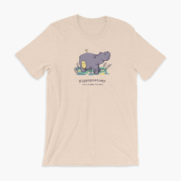 A Hippo or Hippopotamus with an ostomy bag — also known as a Hippopostomy. He is standing in some foliage smiling and has a bird on his back on a heather dust adult t-shirt.