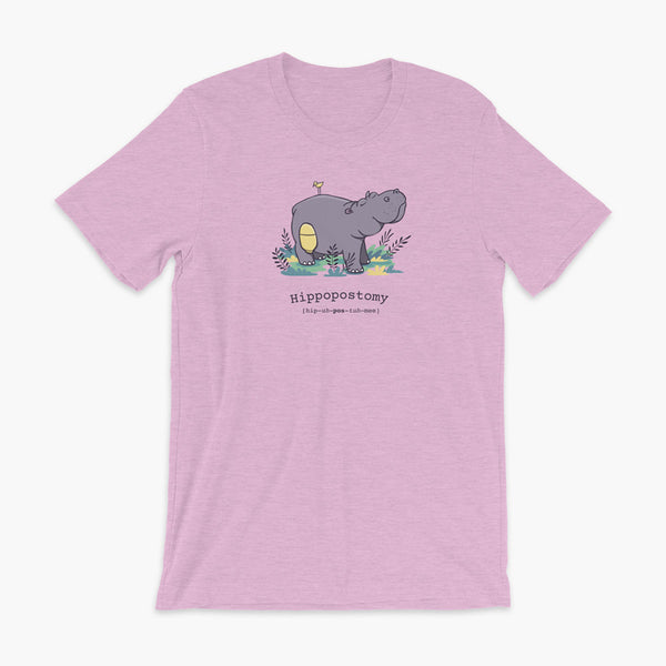 A Hippo or Hippopotamus with an ostomy bag — also known as a Hippopostomy. He is standing in some foliage smiling and has a bird on his back on a heather prism lilac adult t-shirt.