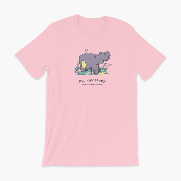 A Hippo or Hippopotamus with an ostomy bag — also known as a Hippopostomy. He is standing in some foliage smiling and has a bird on his back on a Pink adult t-shirt.