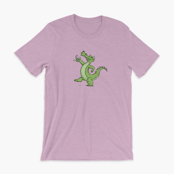 A green alligator or crocodile walks confidently with a big smile after bing decannulated of trach free. It is holding the trach in his hand. One a heather prism lilac adult t-shirt