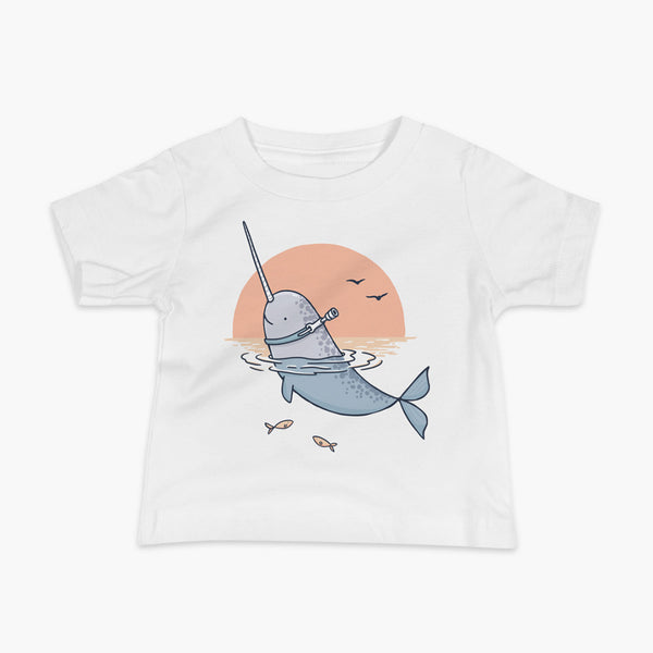 A Narwhal that has a trach or tracheostomy pokes his head and horn through the water in front of a setting sun. He has a naturally built in stoma. It is on a white infant t-shirt.