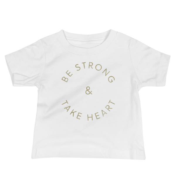 Gold text that says Be Strong & Take Heart in a circle on an infant white t-shirt by StomaStoma for g-tube and trach life empowerment.