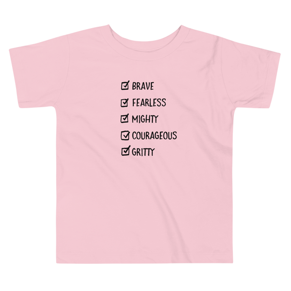 A checklist of text all checked off with the words brave, fearless, mighty, courageous, gritty on a pink kids t-shirt.