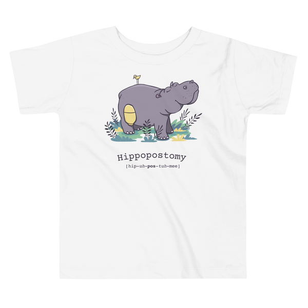 A Hippo or Hippopotamus has a stoma with an ostomy bag — also known as a Hippopostomy. He is standing in some foliage smiling and has a bird on his back on a white kids t-shirt.