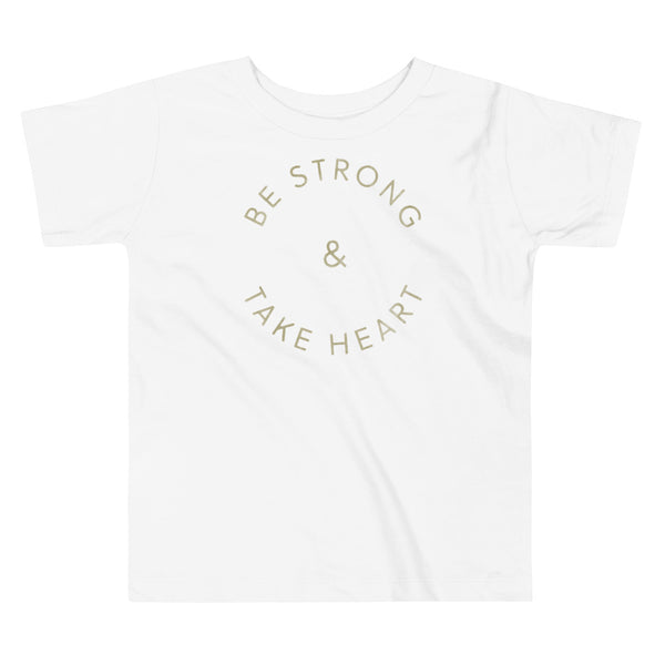 Gold text that says Be Strong & Take Heart in a circle on a kids white t-shirt by StomaStoma for g-tube and trach life empowerment.
