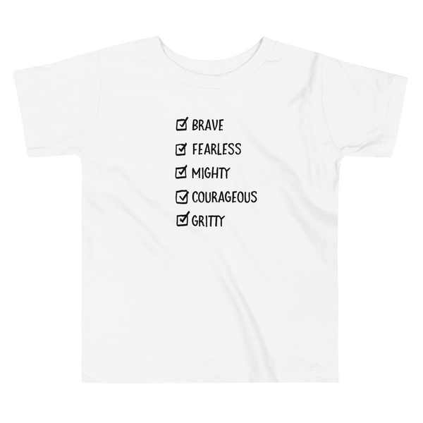 A checklist of text all checked off with the words brave, fearless, mighty, courageous, gritty on a white kids t-shirt.