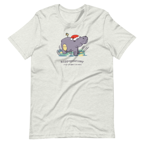 A Hippo or Hippopotamus with an ostomy bag — also known as a Hippopostomy. He is standing in some foliage smiling and has a bird on his back with a Christmas hat on an ash adult t-shirt.