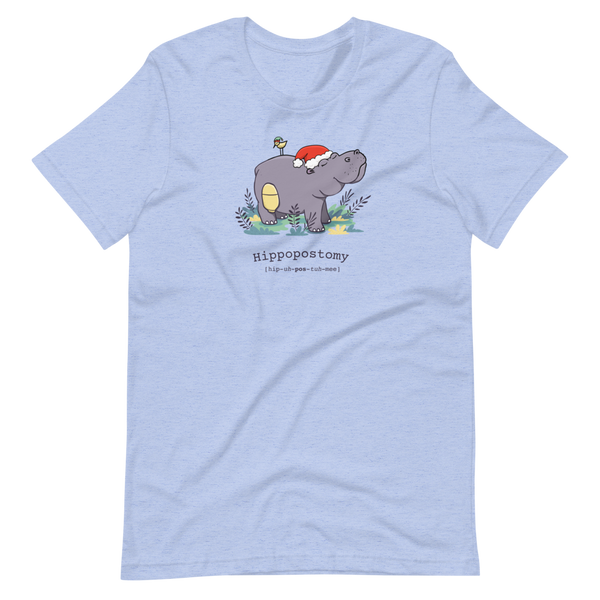 A Hippo or Hippopotamus with an ostomy bag — also known as a Hippopostomy. He is standing in some foliage smiling and has a bird on his back with a Christmas hat on a heather blue adult t-shirt.