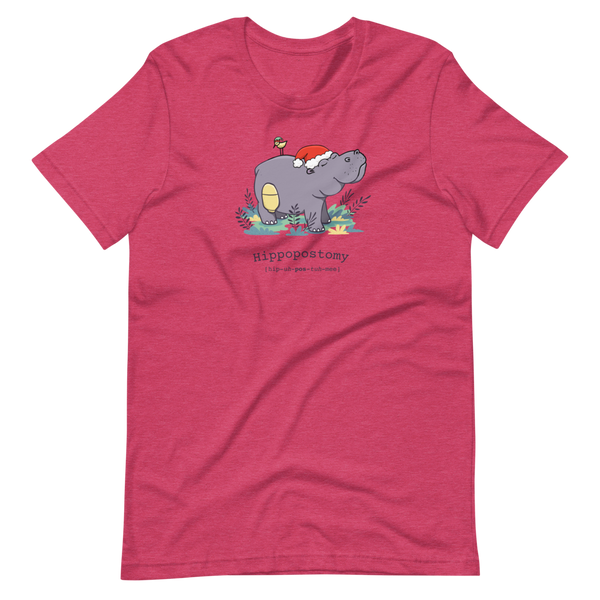 A Hippo or Hippopotamus with an ostomy bag — also known as a Hippopostomy. He is standing in some foliage smiling and has a bird on his back with a Christmas hat on a heather raspberry adult t-shirt.